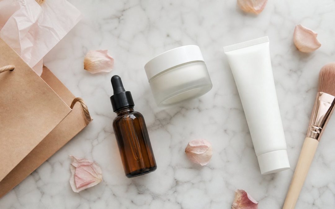 Flacons de soins beauté non marqués posés sur un plan en marbre avec un sac cadeau en papier kraft